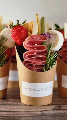 some food is sitting in small cups on a wooden table with strawberries and other foods