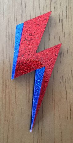 a red and blue lightning bolt brooch sitting on top of a wooden table