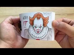 a person holding up a book with a drawing of a clown on it