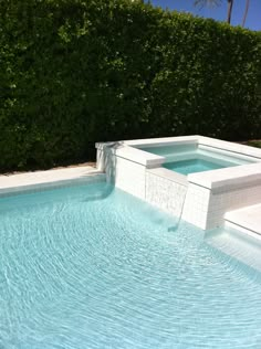 an empty swimming pool in front of a hedge