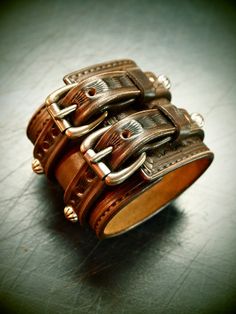 "This brown leather cuff uses natural vegetable-tanned leather and is Hand tooled,scribed,edged,studded and stamped with an original border design. Antiqued silver concho spots run 2 straps over the main cuff. I use Western techniques and no electric tools. It is finished in vintage walnut dye, distressed and hand rubbed creating a unique vintage look. Aged brass buckles and vintage copper rivets provide the closure I'll need your wrist size for this cuff! I Can size it for men or women Instruct Leather Concho Cuff Bracelet, Leather Cuff Bracelet With Concho, Rustic Leather Concho Bracelets, Vintage Leather Concho Bracelets, Punk Leather Cuff Wristband, Western Style Hand Tooled Leather Bracelets, Brown Leather Concho Bracelet, Western Leather Concho Cuff Bracelet, Leather Cuff Bracelets With Custom Hardware