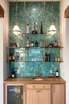 a kitchen with green tiles and gold fixtures on the wall, along with wooden cabinets