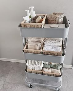 a cart with towels, soaps and other items in it on the floor next to a wall