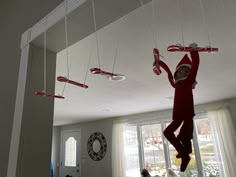 an elf is hanging upside down from the ceiling with his arms and legs in the air