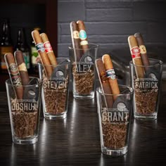 six shot glasses filled with cigars on top of a table