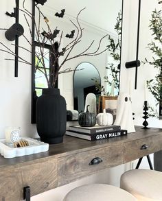 a wooden desk topped with a mirror and a vase filled with flowers on top of it