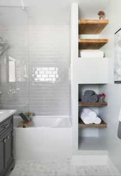 a bathroom with gray cabinets and white tile on the walls, along with a bathtub