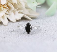 a black and white diamond ring sitting on top of a table next to some flowers