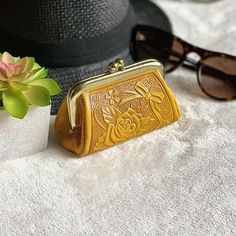 a yellow purse sitting on top of a table next to sunglasses and a flower pot