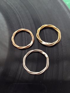 three gold and silver rings on top of a black record player's turntable