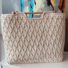 a handbag sitting on top of a white table next to a painting and wooden handles