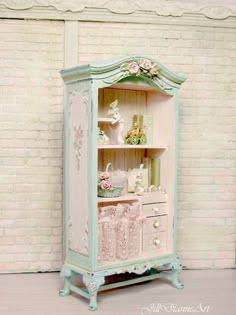 a pink and blue cabinet with flowers on it's shelves, decorated with lace