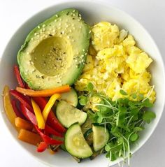 a white bowl filled with vegetables and an avocado