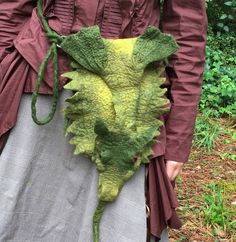 a woman is holding a green plant with long stems attached to it's back