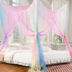 a bed with pink, blue and white drapes on it