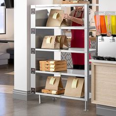 a woman standing in front of a shelf filled with boxes and paper bags on it