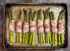 asparagus wrapped in bacon on a baking sheet