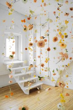 a staircase with flowers on the wall and some stairs going up to it in front of a window