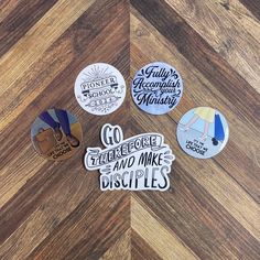 six badges with words on them sitting on a wooden floor