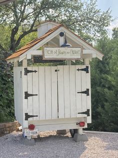 a small white outhouse sitting on top of gravel