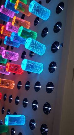 there are many bottles on the wall with lights in them that look like they have been made out of plastic bottle caps