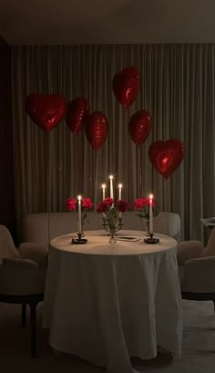 a table with candles and red heart balloons