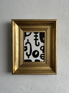 a gold frame hanging on the wall with a black and white pattern