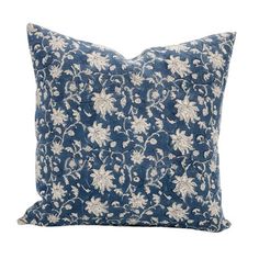 a blue and white pillow with flowers on the front, sitting on a white background