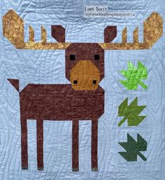 a quilted wall hanging with a moose and leaves on it's side,