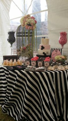 a table topped with lots of cakes and cupcakes next to a birdcage