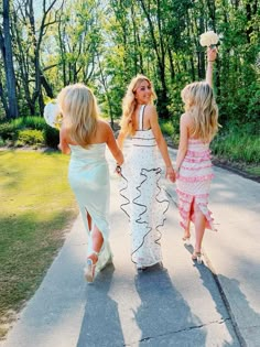 three girls walking down the sidewalk holding hands