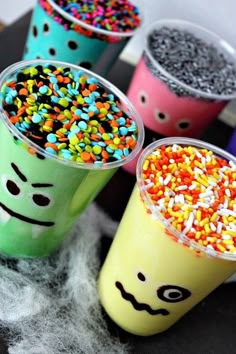 three cups filled with sprinkles and candy on top of a black table