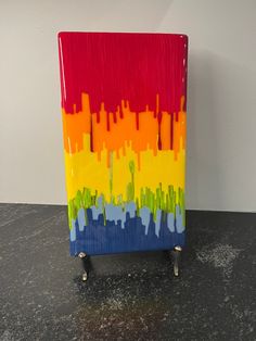 a colorful piece of art sitting on top of a black table next to a white wall