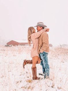 a man and woman standing in the snow with their arms around each other as they kiss