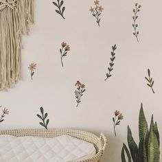 a wall with flowers and plants painted on it, next to a wicker basket