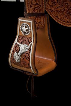 the back of a horse saddle with a cow on it's side and an embroidered design