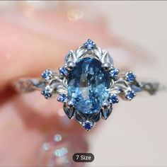 a close up of a ring with a blue stone in the center and diamonds around it