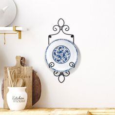 a blue and white plate sitting on top of a wooden shelf next to a cutting board