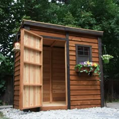 a small wooden shed with its door open and flowers growing out of the window sill