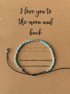 a card that says i love you to the moon and back with a blue beaded bracelet