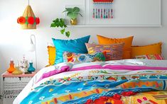 the bed is covered with colorful pillows and blankets