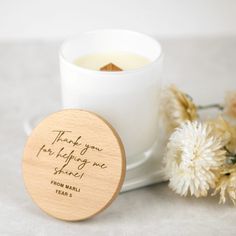 a wooden coaster next to a white cup filled with tea and flowers on a table