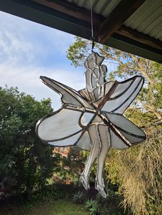 a stained glass flower hanging from the side of a building with trees in the background