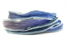 several different colors of thread on a white surface with one purple and one blue color