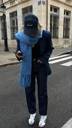 a woman walking down the street while wearing a hat and scarf