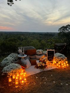 candles are lit on the ground in front of an outdoor seating area with pillows and flowers