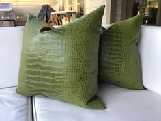 two green pillows sitting on top of a white couch