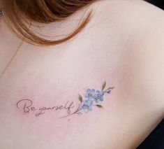 a woman with a tattoo on her chest that says be yourself and flowers are in the foreground