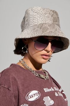 Scale it back in The AKIRA Label Tina Snake Bucket Hat. This stylish accessory is crafted from a textured, scale-like faux leather base and features a snakeskin pattern throughout, a floppy bucket hat silhouette, a flat crown, a paneled construction, a wide downturned brim, and a satin inner lining.   - Shell Surface: 100% PU, Shell Base: 100% Viscose, Lining: 100% Polyester- Imported (all measurements approximate from size O/S)- 22” Head Circumference- 30” Brim Circumference- 6.5” Head Diameter Product ID: 441134 Bucket Hat Sunglasses, Bucket Hat Inspo, Floppy Bucket Hat, Hat Silhouette, Bucket Hat Style, Snakeskin Pattern, Hat Style, Head Circumference, Stylish Accessories