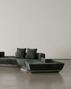 a large gray couch sitting on top of a floor next to a white wall in a room